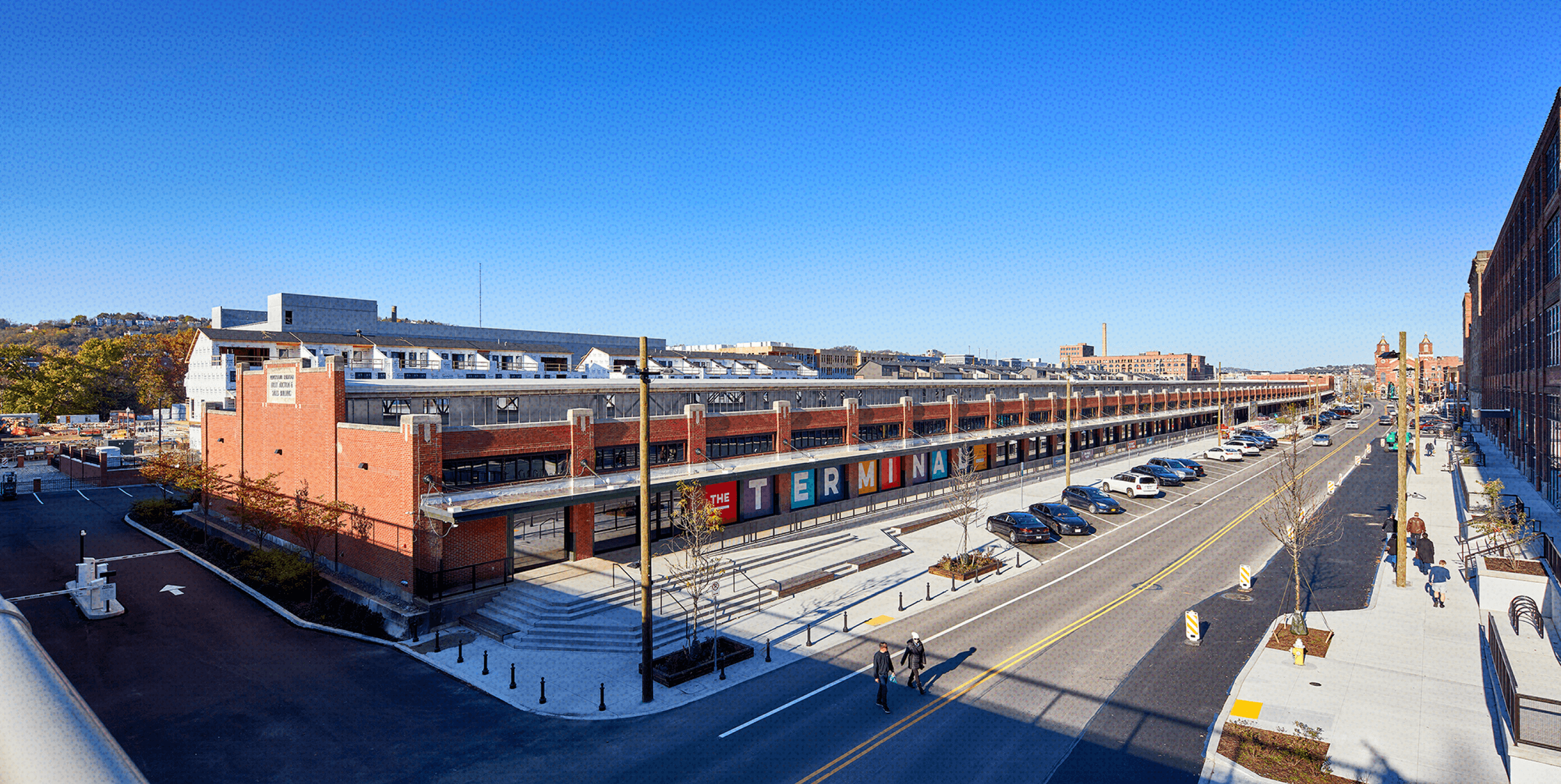 an overhead, isometric view of the Strip District Terminal, a long, low brick building, with a road with parked cars abutting it